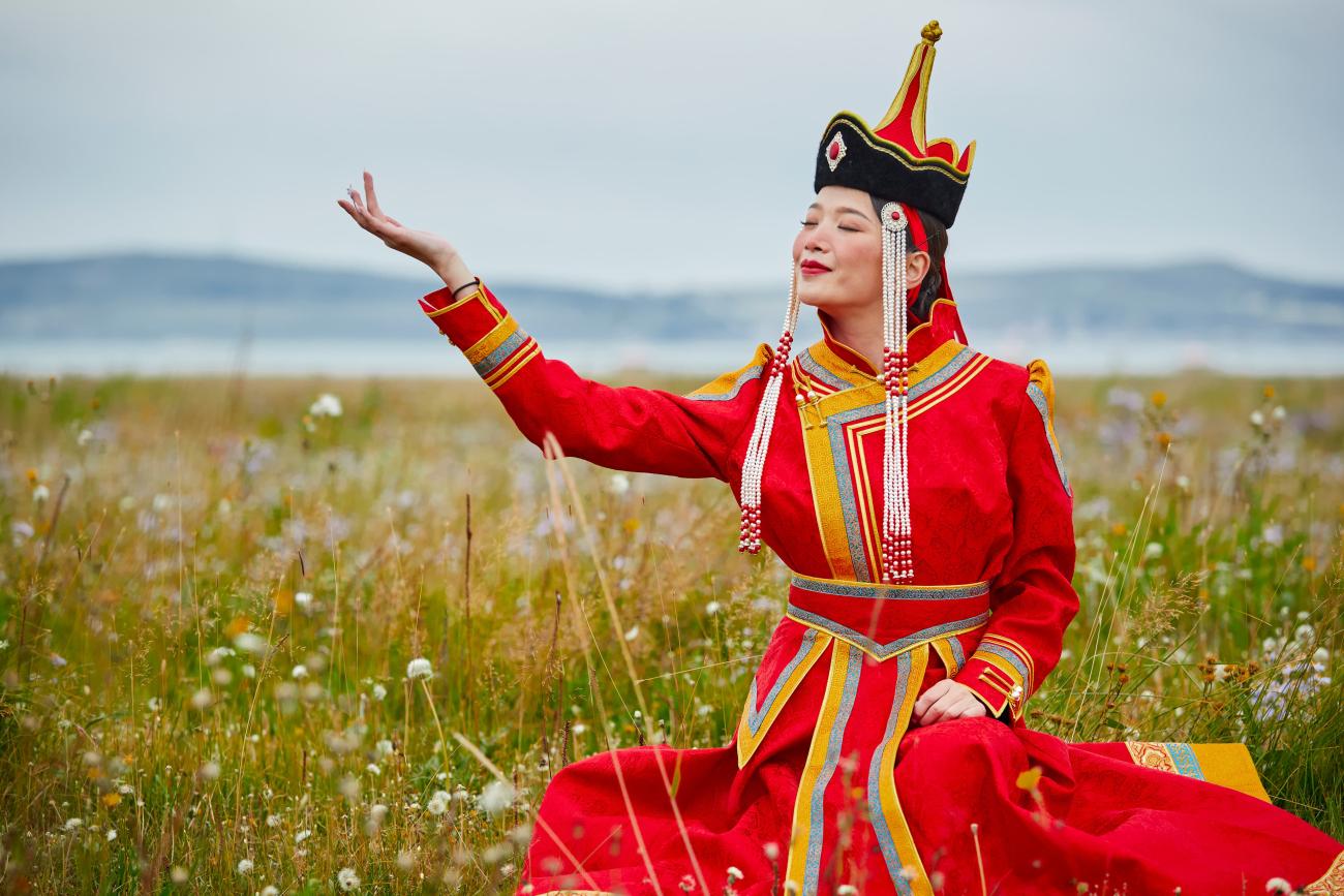 Woman in traditional Mongolian clothing in a meadow of flowers